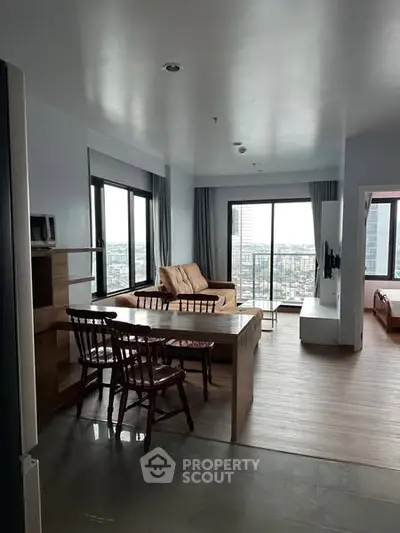 Modern apartment with open living room and dining area, featuring large windows and city view.