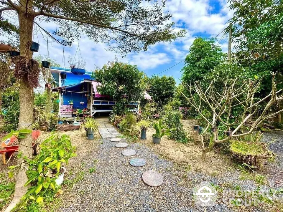 Charming garden view with lush greenery and quaint blue house, perfect for nature lovers seeking tranquility.