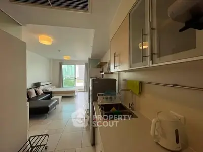 Modern apartment kitchen with open layout and cozy living area, featuring sleek cabinetry and natural light.