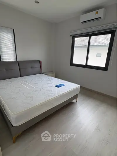 Modern bedroom with large window and air conditioning, featuring a comfortable bed and minimalist decor.
