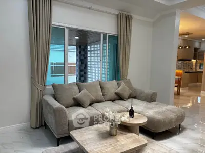 Spacious living room with modern beige sofa and elegant decor, perfect for relaxation and entertaining.
