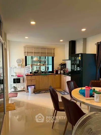 Modern kitchen with open layout and dining area, featuring sleek cabinetry and ample natural light.