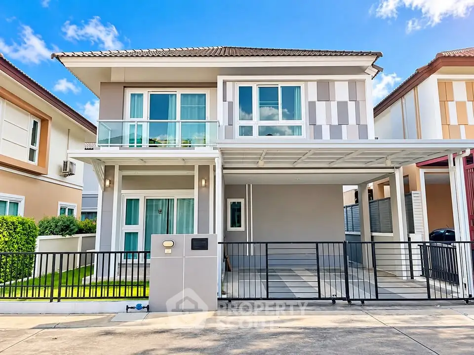 Modern two-story house with balcony and carport in a suburban neighborhood.