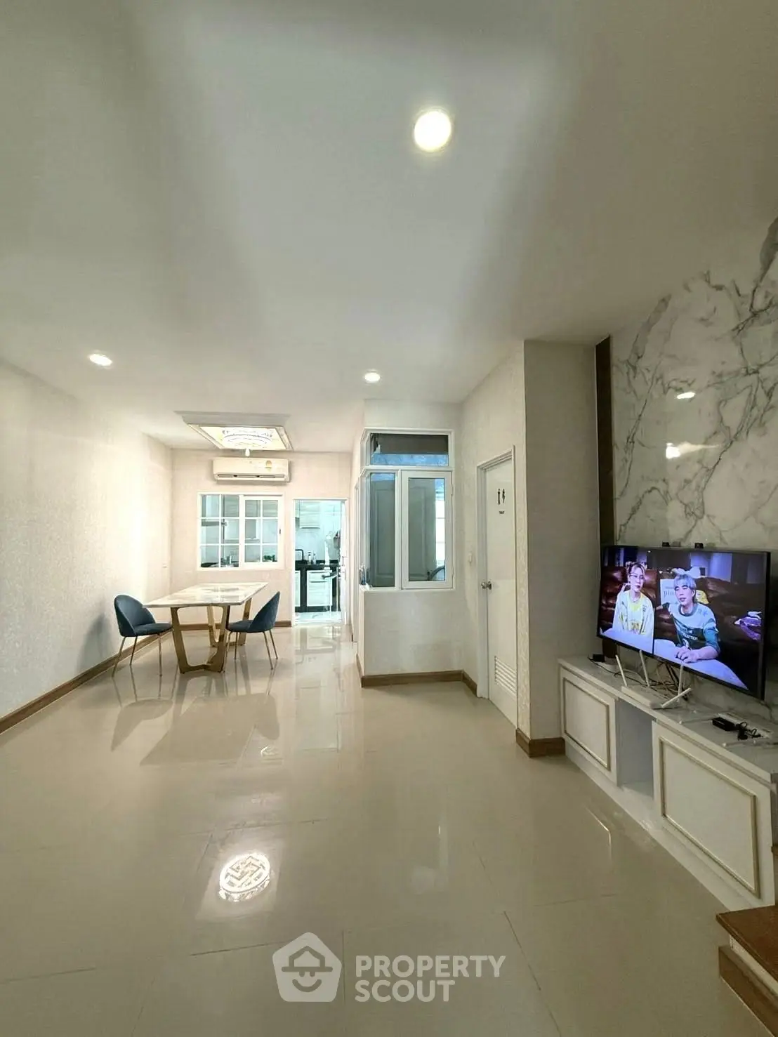 Spacious modern living room with dining area and TV, featuring elegant marble accents.