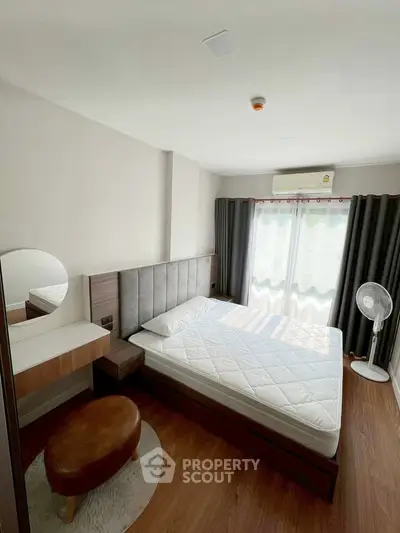 Modern bedroom with natural light, featuring a stylish bed, wooden flooring, and elegant curtains.