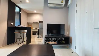 Modern living room with open kitchen, featuring sleek furniture and contemporary design.