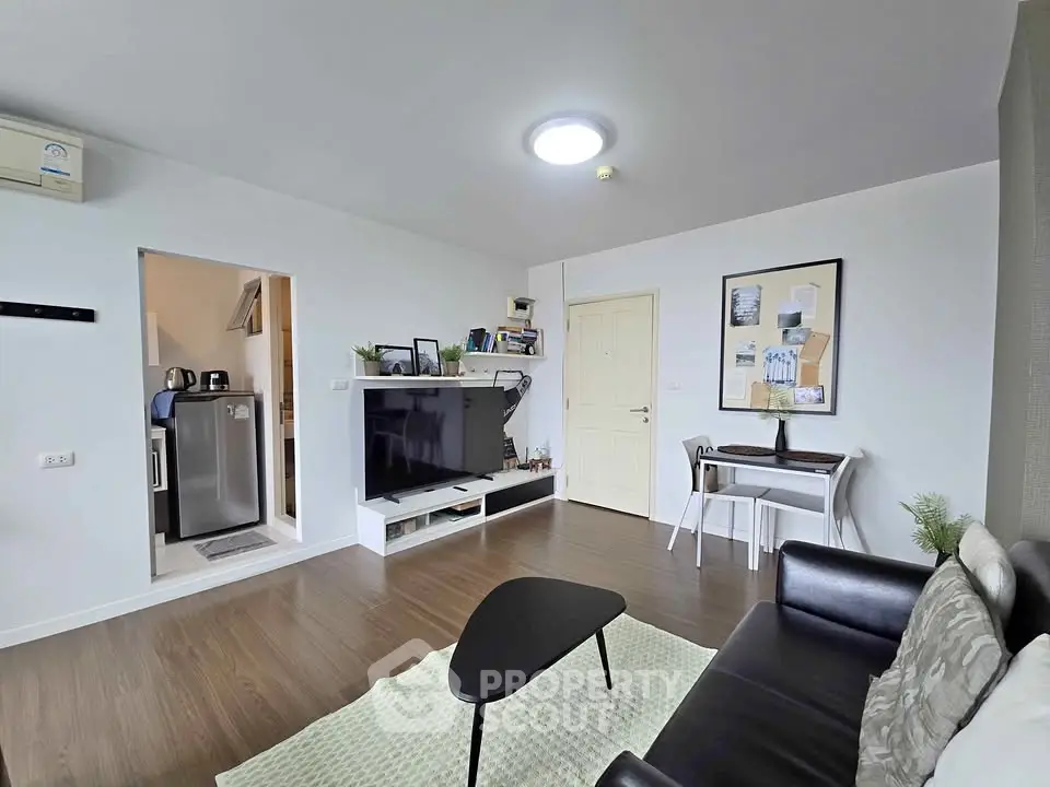 Modern living room with sleek furniture and large TV, featuring a cozy workspace corner.