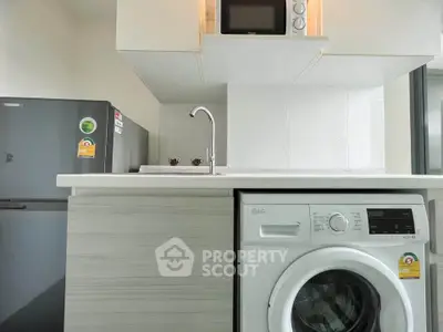 Modern kitchen with washing machine and fridge in compact layout