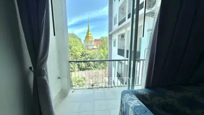 Charming balcony view with lush greenery and a glimpse of a golden spire.