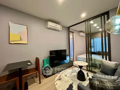 Modern living room with stylish decor and glass partition leading to bedroom