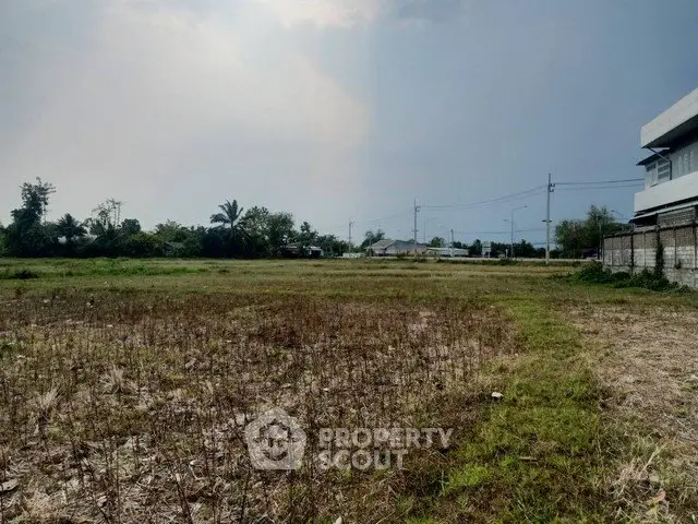 Expansive vacant land with potential for development, surrounded by greenery and clear skies.