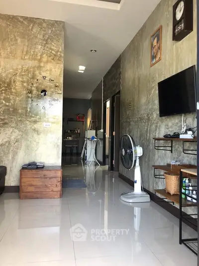 Modern living room with polished floors, wall clock, and mounted TV, featuring sleek decor and natural lighting.