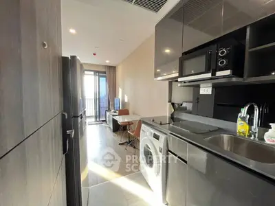 Modern kitchen with sleek appliances and open layout leading to a bright living area with balcony access.