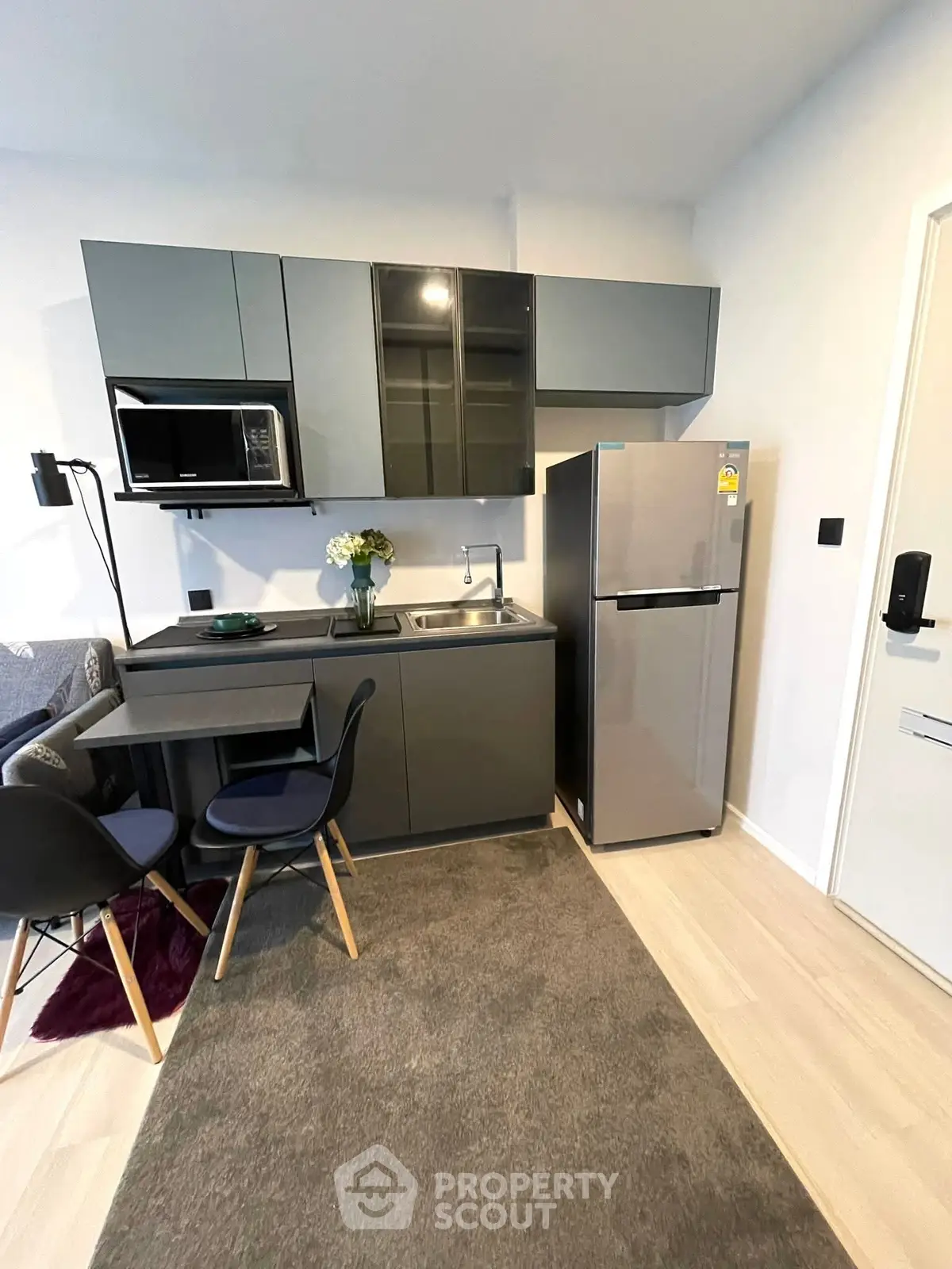 Modern compact kitchen with sleek cabinets and stainless steel appliances in cozy apartment.