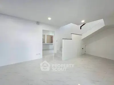 Spacious modern living room with sleek white tiles and staircase, perfect for contemporary living.