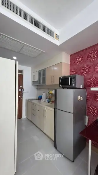 Modern kitchen with sleek cabinets and stainless steel fridge in a compact layout.
