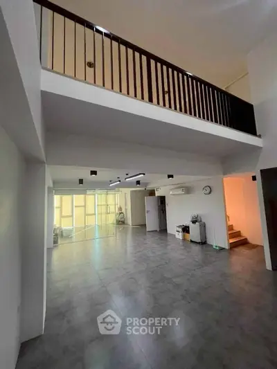 Spacious modern living room with high ceiling and mezzanine, perfect for stylish urban living.