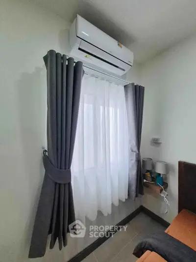 Cozy bedroom corner with air conditioning and elegant curtains, perfect for comfort and relaxation.