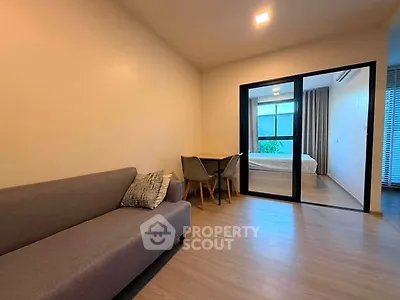 Modern apartment with cozy living room and bedroom separated by glass doors.