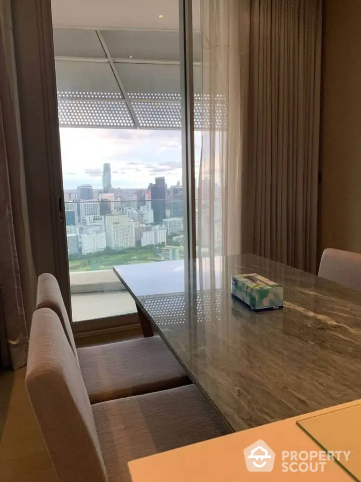 Luxurious dining area with stunning city view from high-rise apartment balcony.