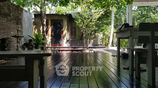 Charming outdoor patio with lush greenery and wooden deck, perfect for relaxation and entertaining.