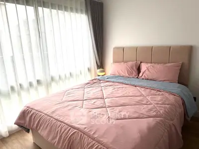 Cozy bedroom with soft pink bedding and large window for natural light