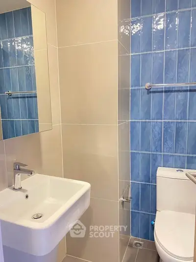 Modern bathroom with blue tiled wall and sleek white fixtures