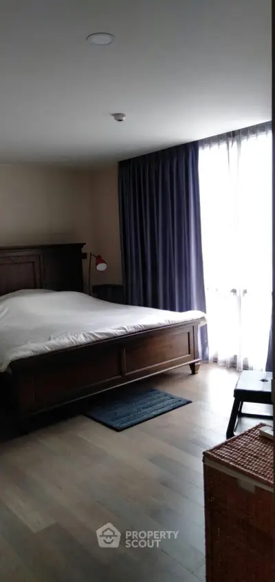 Spacious bedroom with elegant wooden furniture and large window for natural light.
