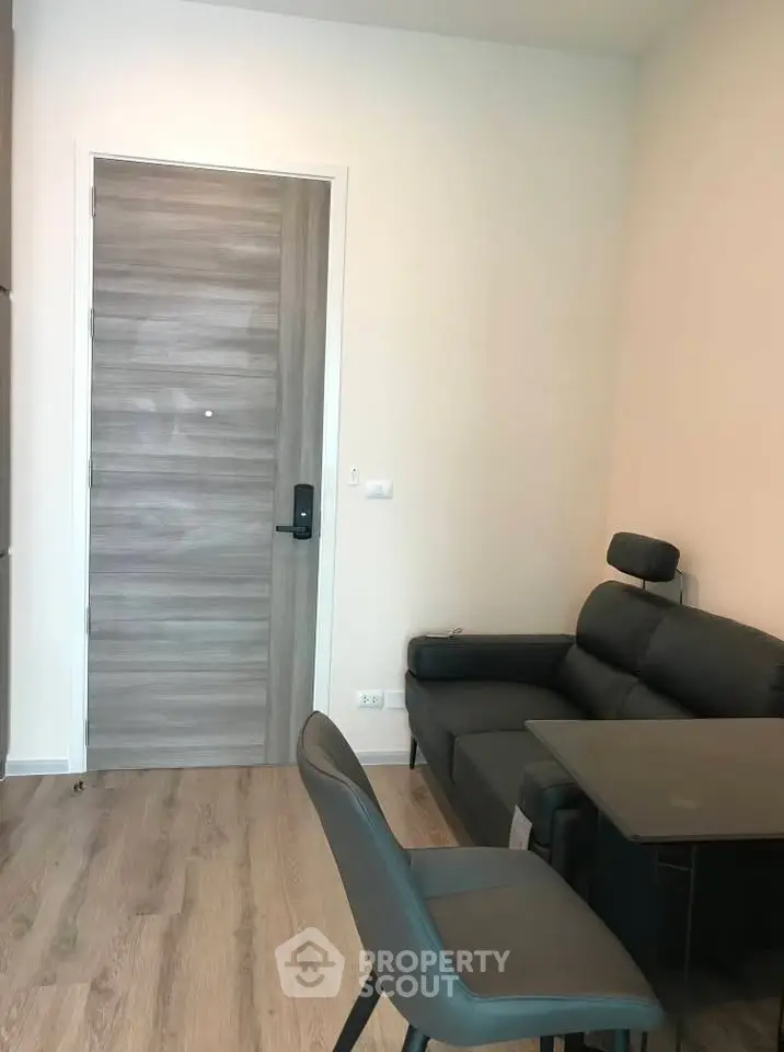 Modern living room with sleek furniture and wooden flooring, featuring a stylish entrance door.