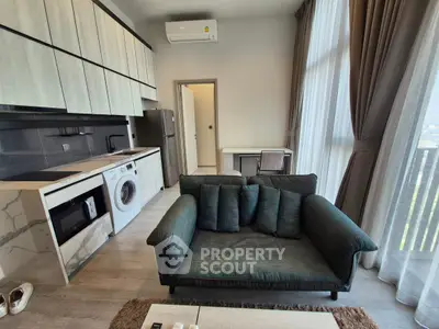 Modern living room with open kitchen, featuring washing machine and stylish sofa, perfect for urban living.