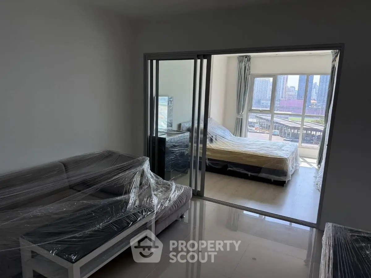 Modern apartment with spacious living room and bedroom, featuring city view and sleek furnishings.