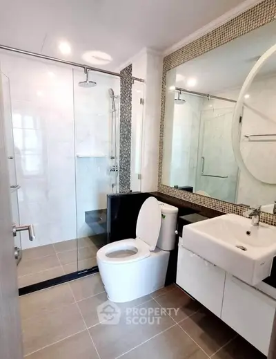 Modern bathroom with glass shower, large mirror, and sleek fixtures in a contemporary home.