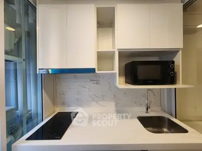 Modern kitchen with sleek cabinetry, built-in microwave, and induction cooktop in a compact layout.