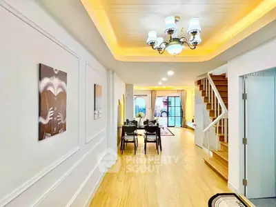 Elegant open-plan living and dining area with modern lighting and wooden flooring.