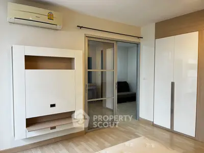 Modern bedroom with sliding door and built-in wardrobe, featuring sleek design and air conditioning.