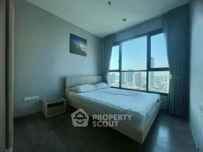 Modern bedroom with large window offering stunning city view, featuring minimalist decor and cozy ambiance.