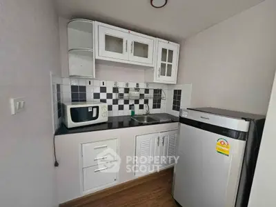Compact kitchen with modern appliances and stylish cabinetry in a cozy apartment.