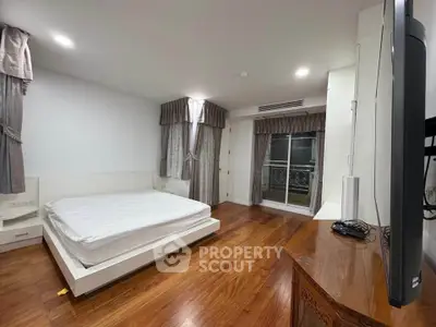 Spacious bedroom with wooden flooring and elegant curtains in modern apartment