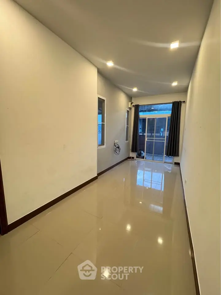 Spacious empty room with glossy tiled floor and large window, perfect for customization.
