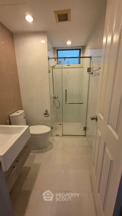 Modern bathroom with glass shower enclosure and sleek fixtures in a contemporary apartment.