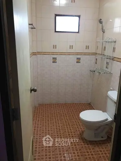 Compact bathroom with tiled walls and floor, featuring a toilet and shower area.