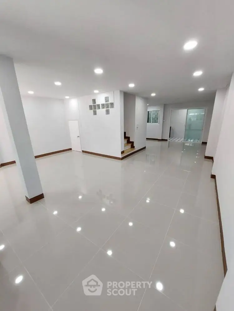 Spacious open-plan living area with modern lighting and sleek tile flooring.