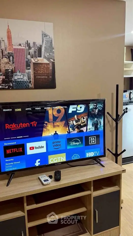 Modern living room with TV and stylish decor, featuring a sleek entertainment unit and cityscape artwork.