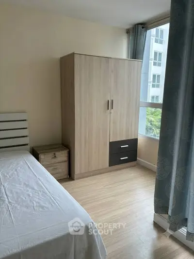Cozy bedroom with wooden wardrobe and large window in modern apartment