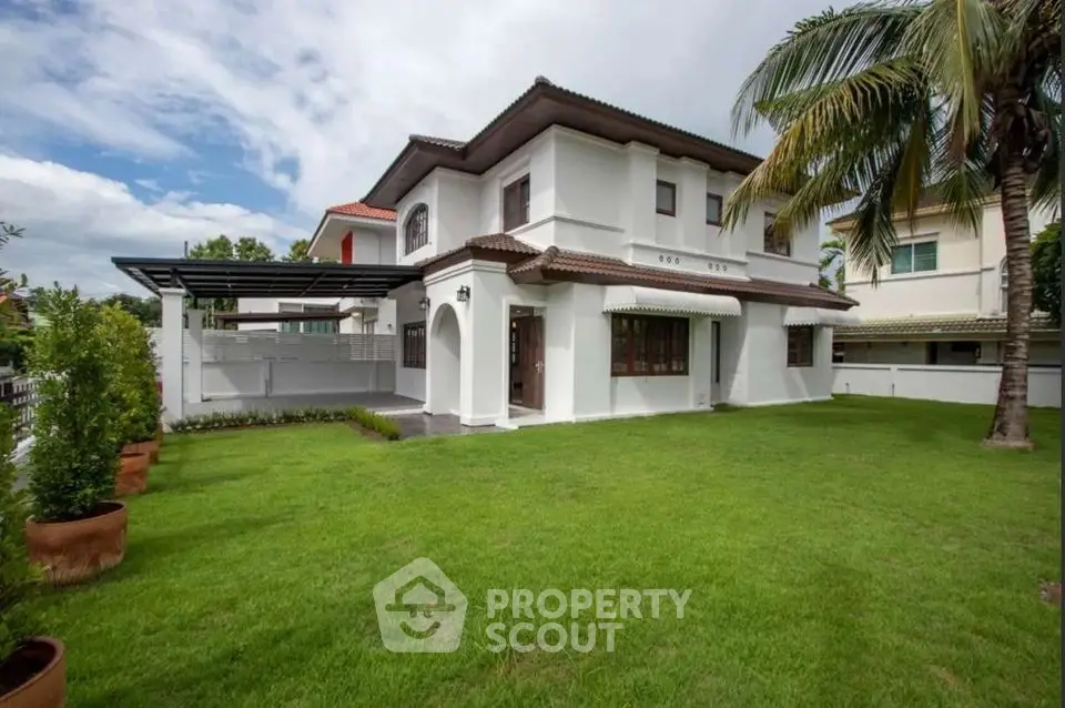 Charming two-story house with lush green lawn and palm tree, perfect for family living.