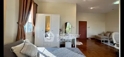 Spacious bedroom with elegant decor and natural light, featuring a cozy seating area and stylish furniture.