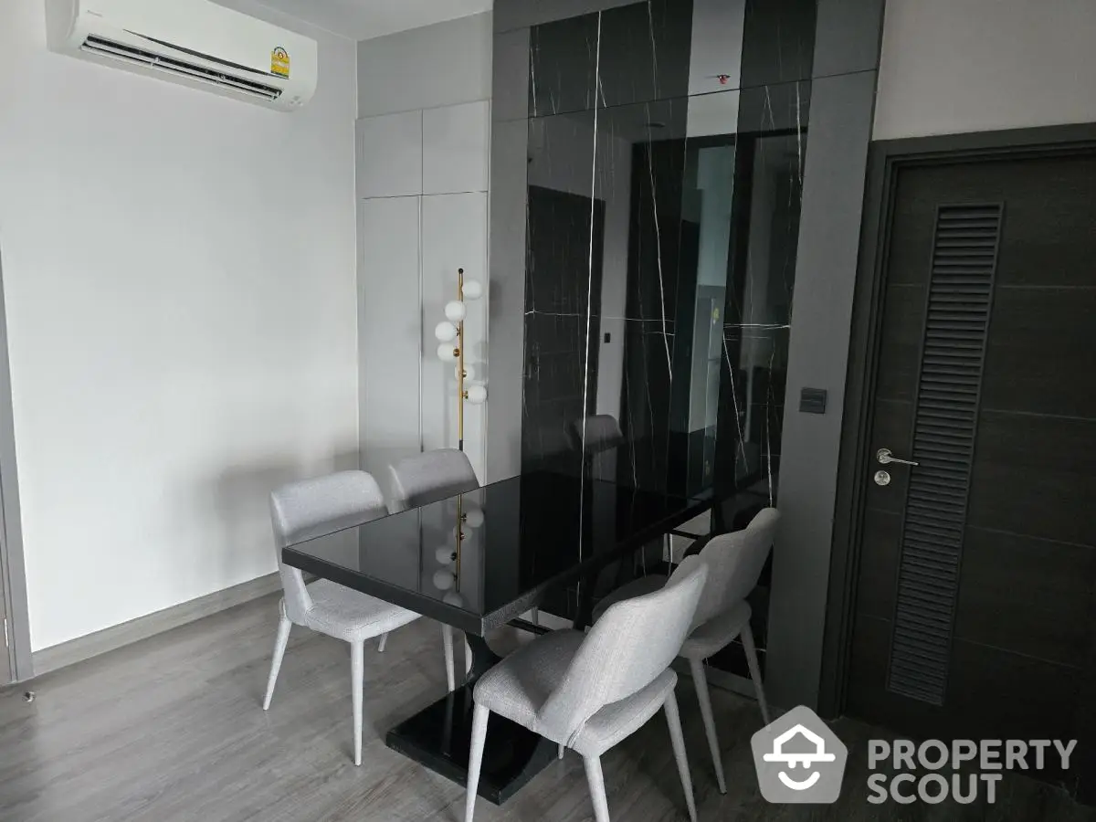 Modern dining area with sleek black table and stylish chairs in contemporary apartment