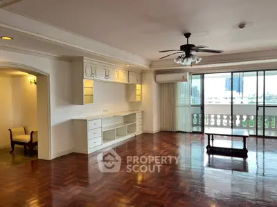 Spacious living room with wooden flooring and large windows in a modern apartment.