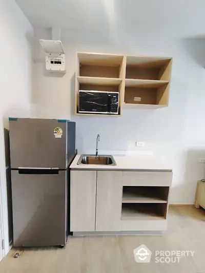 Modern compact kitchen with fridge and microwave in minimalist design