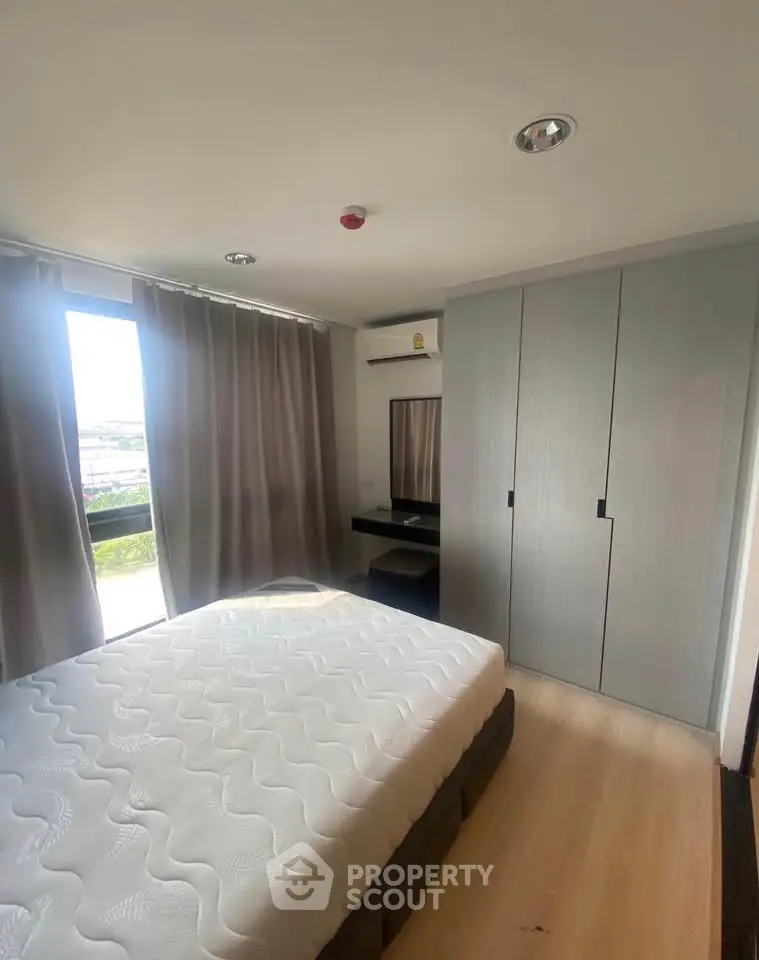Modern bedroom with large window and built-in wardrobe, offering ample natural light and storage space.